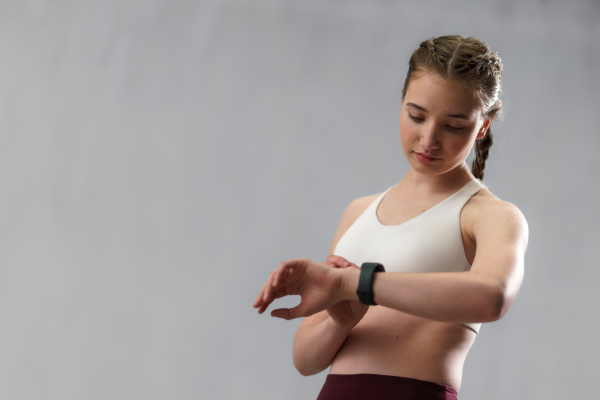 A close up shot of young woman setting and looking at sports smartwatch. Fitness female checking her performance.