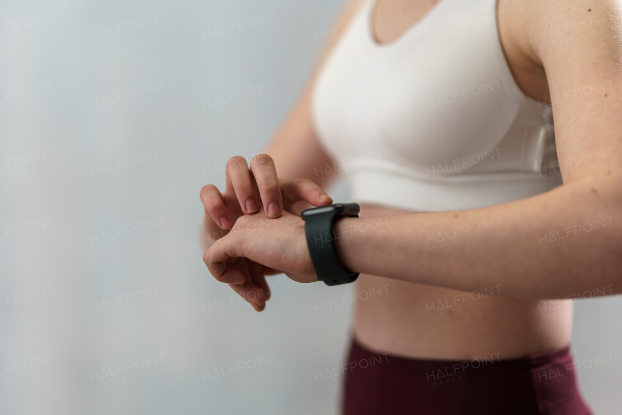 A close up shot of young woman setting and looking at sports smartwatch. Fitness female checking her performance.