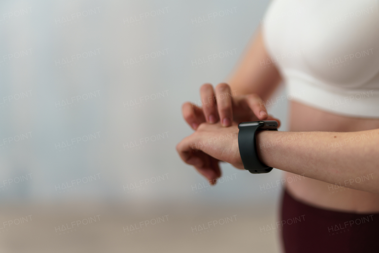 A close up shot of young woman setting and looking at sports smartwatch. Fitness female checking her performance.