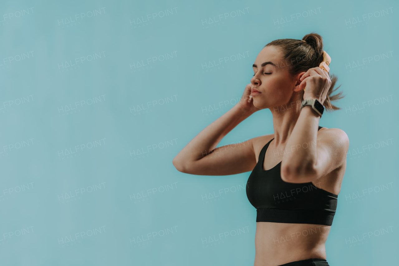 Fitness woman relaxing and listening to music during her workout over green background.