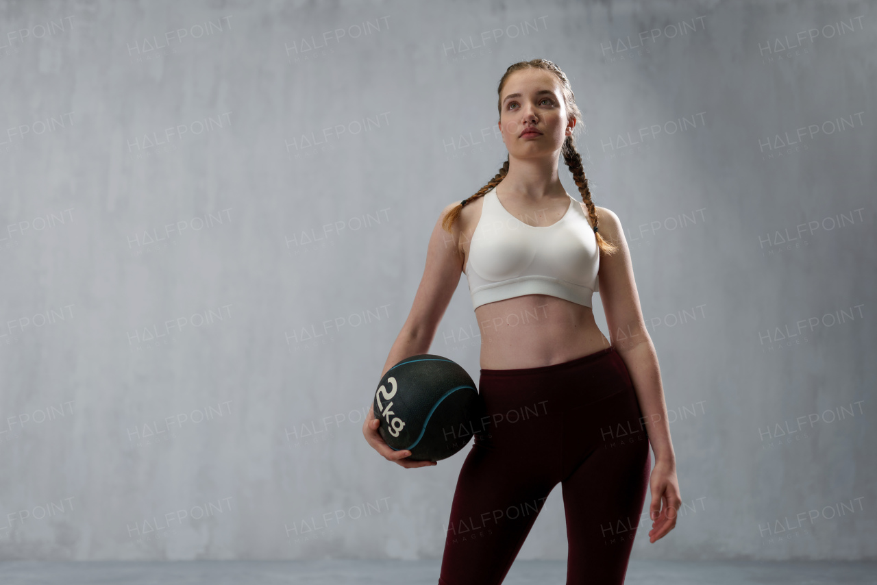 An athletic fitness woman working out with medicine ball on grey background. Copy space.