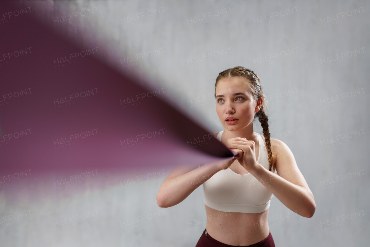 A sports woman in fashion sportswear exercising with elastic band stretch over greay background.