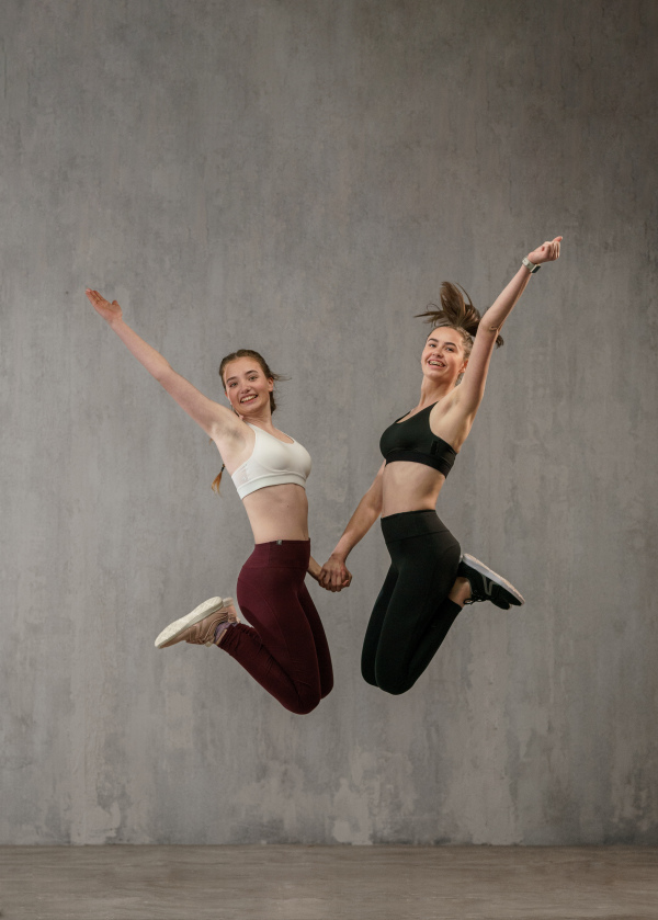 Young beautiful athlete women are posing, umping high in a studio, copy space.