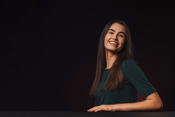 Portrait of a young woman in studio, black background.