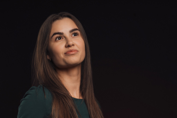 Portrait of a young woman in studio, black background.