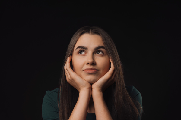 Portrait of a young woman in studio, black background.