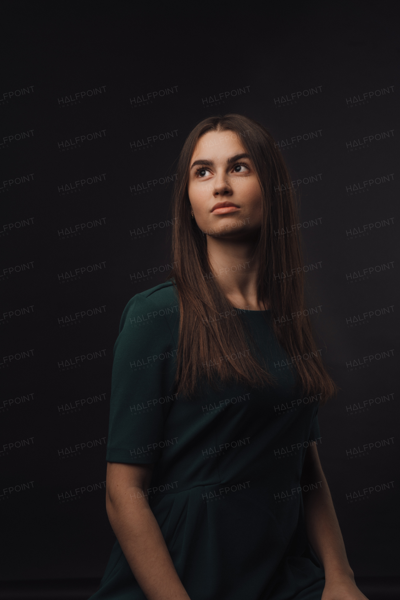 Portrait of a young woman in studio, black background.