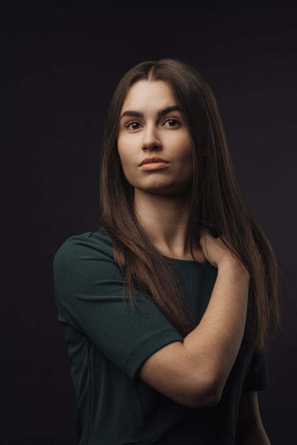 Portrait of a young woman in studio, black background.