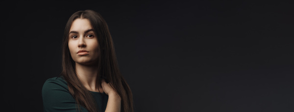 Portrait of a young woman in studio, black background.