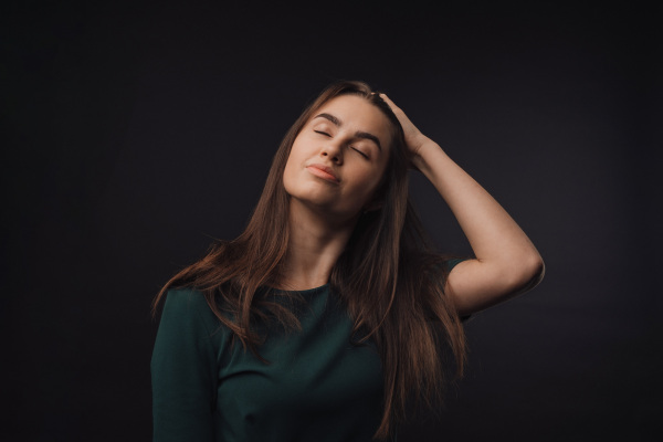 Portrait of a young woman in studio, black background.