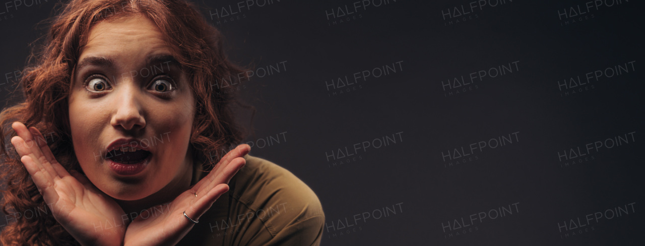 Portrait of a young surprised redhead woman, studio shoot.