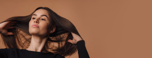 Portrait of a young woman in studio, beige background.