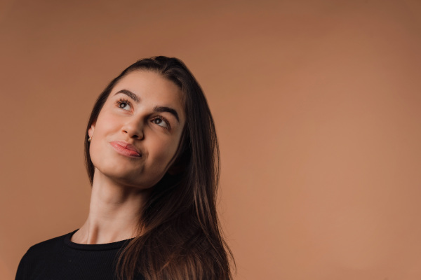 Portrait of a young woman in studio, beige background.