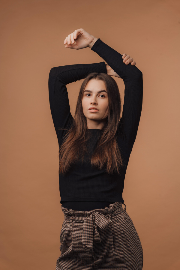 Portrait of a young woman in studio, beige background.