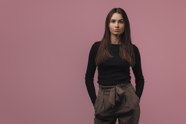 Portrait of a young woman in studio, pink background.