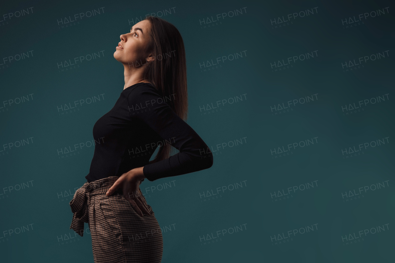 Portrait of a young woman in studio, dark blue background.