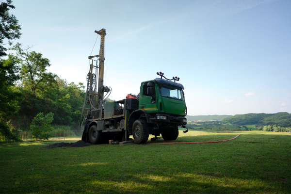 Water well drilling rig, truck preparing to boring dowin into the earth. A rotary drill rig using bits to bore into ground and loosing the soil and rocks. Drilling machine, equipment using water to cool down bits. Mud and muddy water is spitting out when drilling borewell. Banner with copy space.