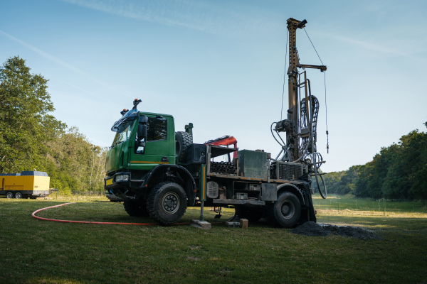 Water well drilling rig, truck preparing to boring dowin into the earth. A rotary drill rig using bits to bore into ground and loosing the soil and rocks. Drilling machine, equipment using water to cool down bits. Mud and muddy water is spitting out when drilling borewell. Banner with copy space.