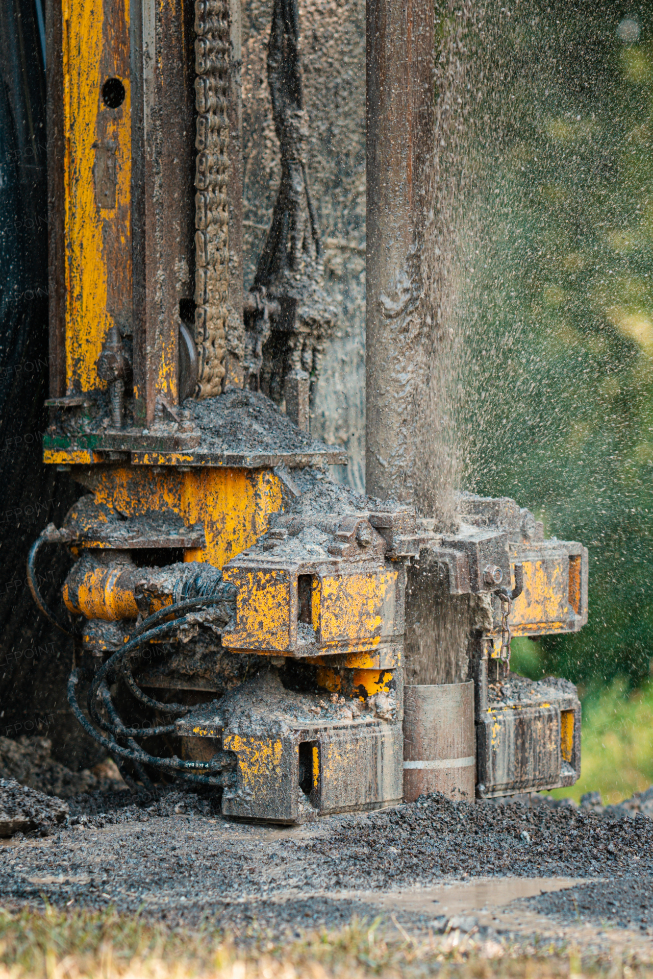 Close up of well drilling rig boring dowin into the earth. A rotary drill rig using bits to bore into ground and loosing the soil and rocks. Drilling machine, equipment using water to cool down bits. Mud and muddy water is spitting out when drilling borewell. Banner with copy space.