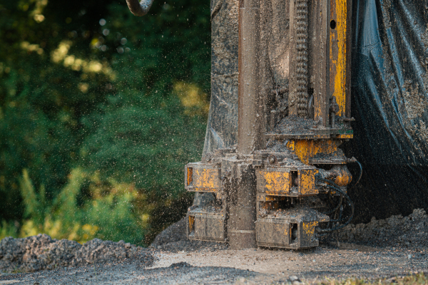 Close up of well drilling rig boring dowin into the earth. A rotary drill rig using bits to bore into ground and loosing the soil and rocks. Drilling machine, equipment using water to cool down bits. Mud and muddy water is spitting out when drilling borewell. Banner with copy space.