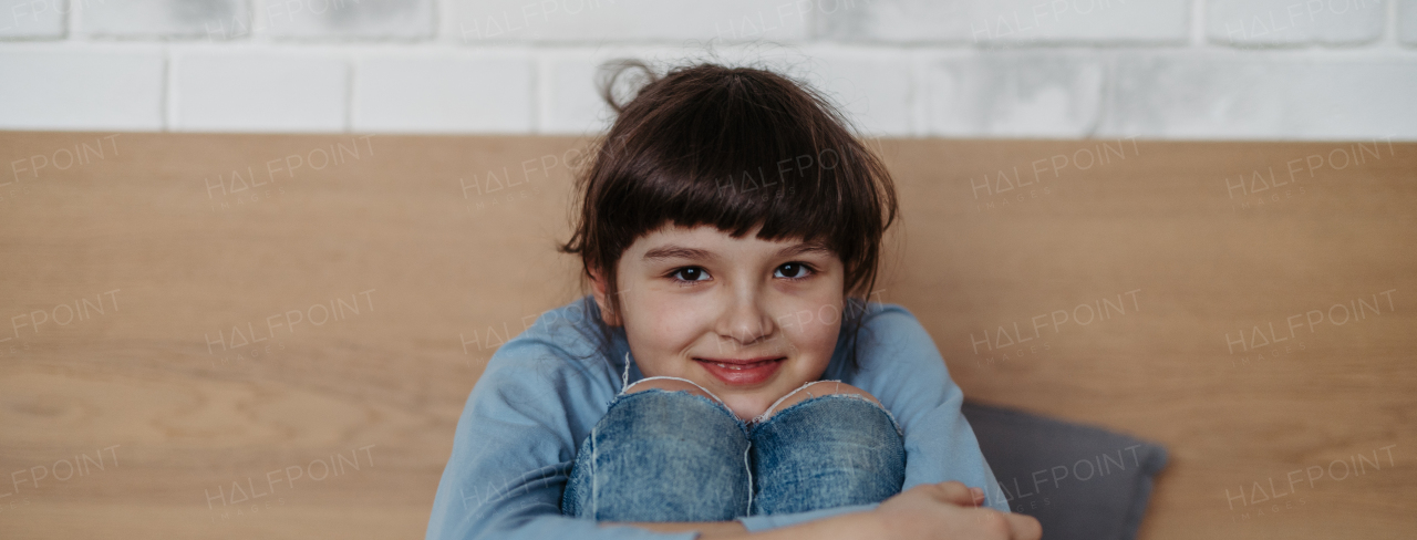 Portrait of a cute young girl. Girl with long hair sitting at home. Banner with copy space.