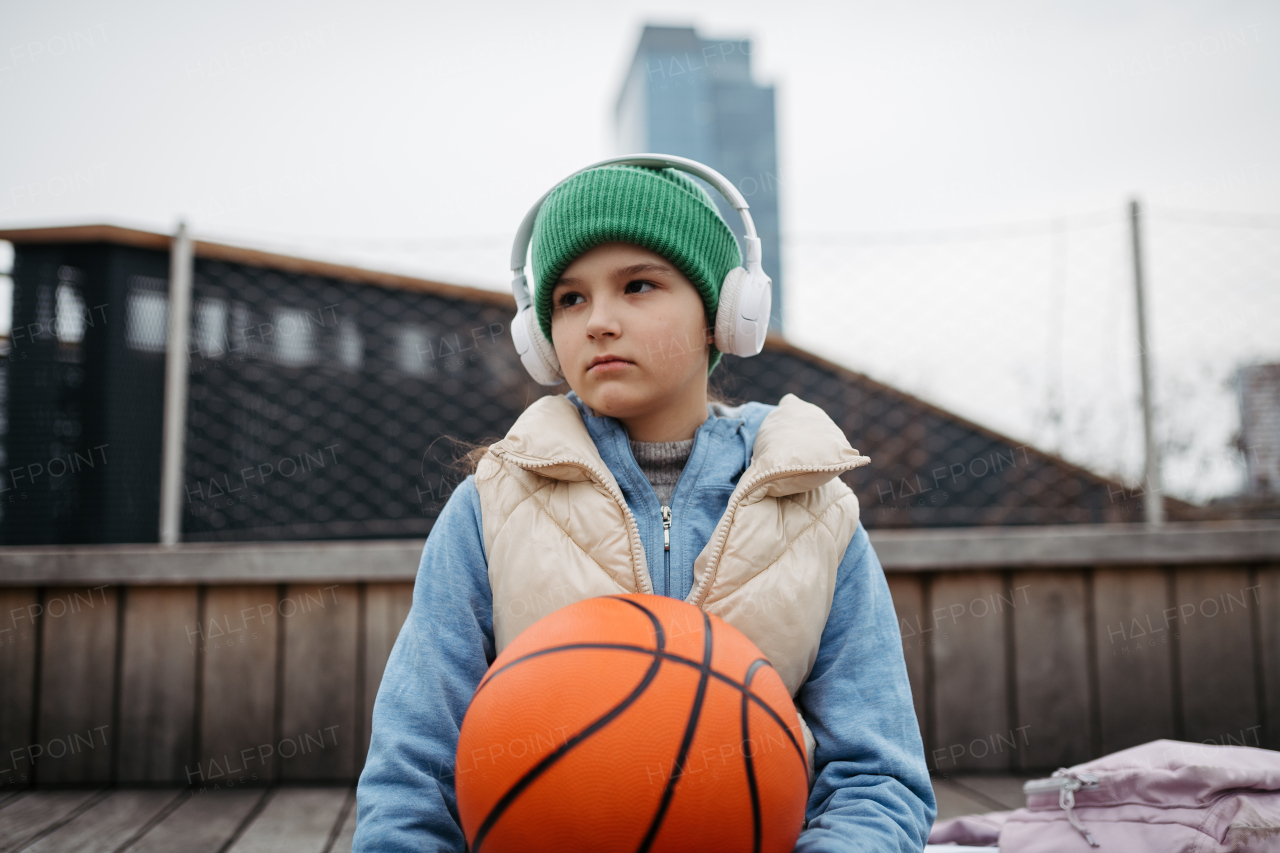 Sad girl alone in the city, want to play basketball. Young girl spending free time alone in the city, no friends. Mental health problems.