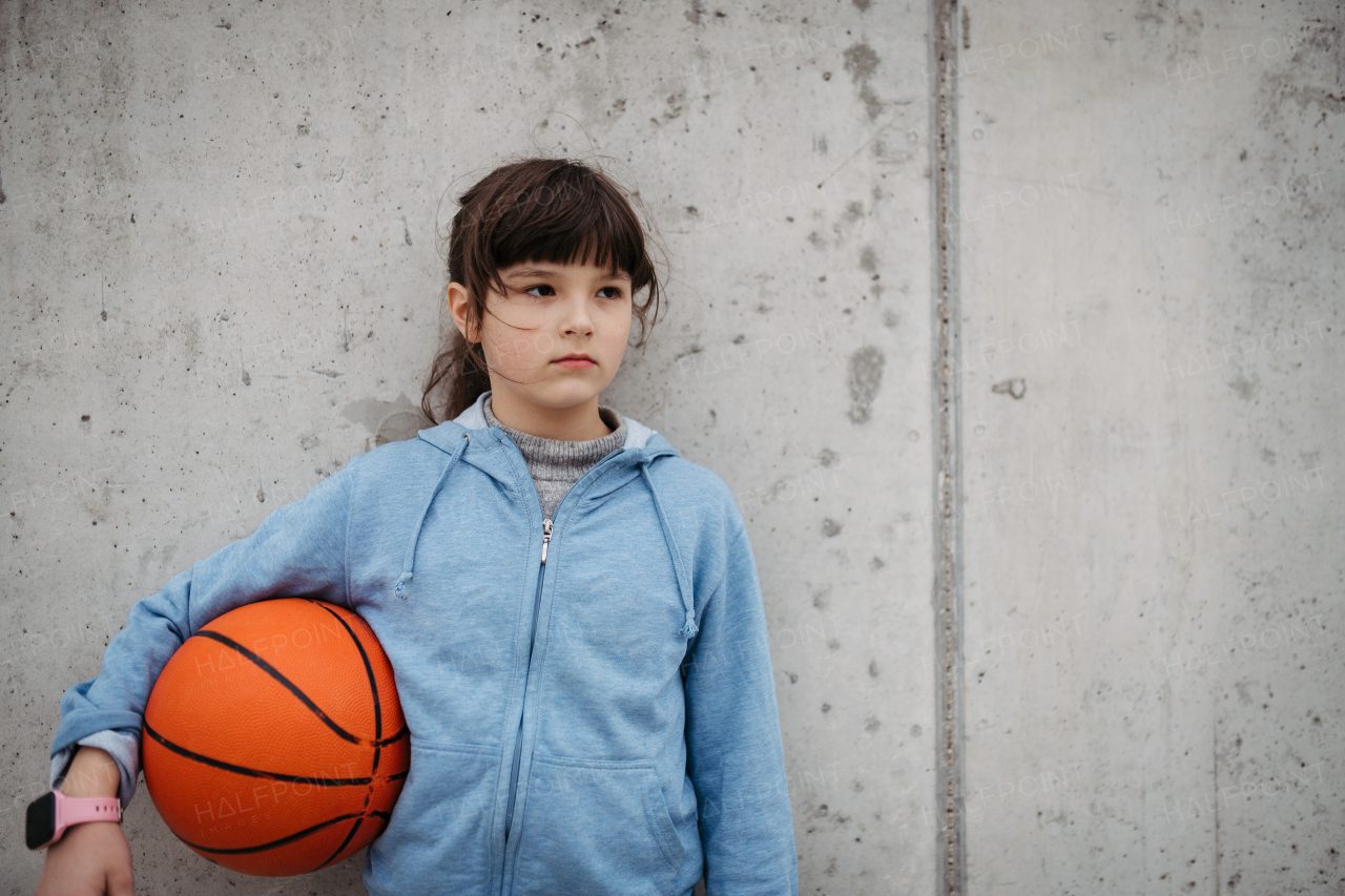 Sad girl alone in the city, want to play basketball. Young girl spending free time alone in the city, no friends. Mental health problems.