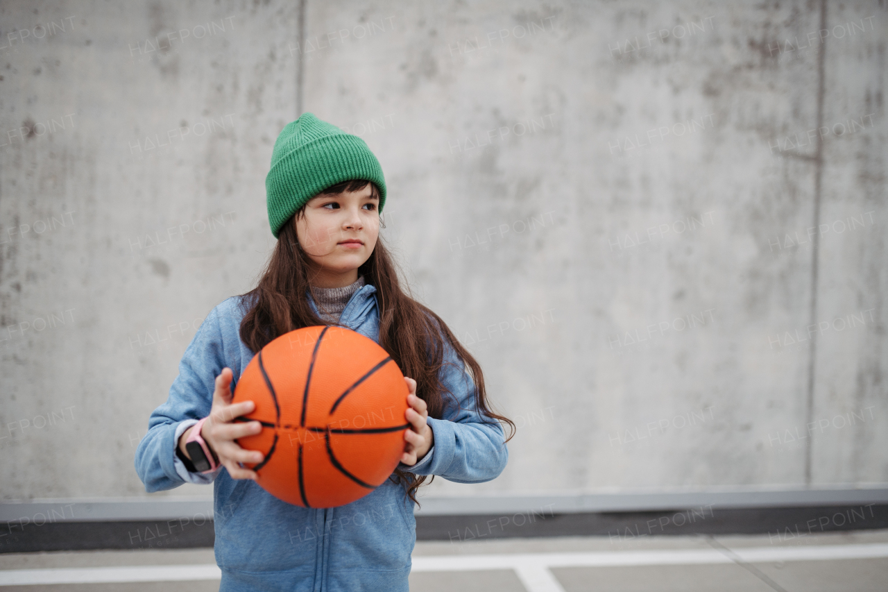 Sad girl alone in the city, want to play basketball. Young girl spending free time alone in the city, no friends, no activity. Mental health problems.