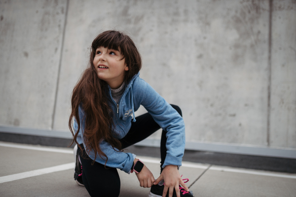 Outdoor portrait of cute young girl, laughing. Girl with a long hair standing on playground in the city.