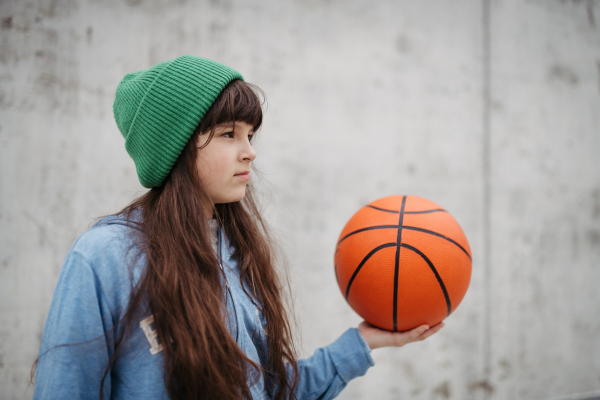 Sad girl alone in the city, want to play basketball. Young girl spending free time alone in the city, no friends. Mental health problems.