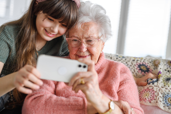 Grandmother with cute girl taking selfie with smartphone. Portrait of an elderly woman spending time with a granddaughter.