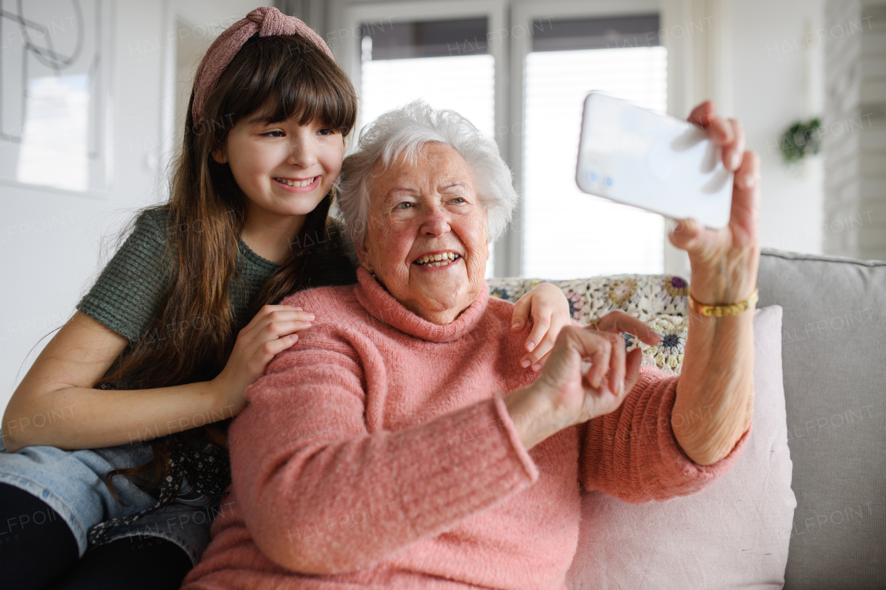 Grandmother with cute girl taking selfie with smartphone. Portrait of an elderly woman spending time with a granddaughter.