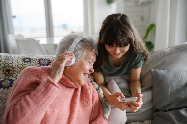 Cute girl showing funny video to gradmother. Portrait of an elderly woman spending time with a granddaughter.