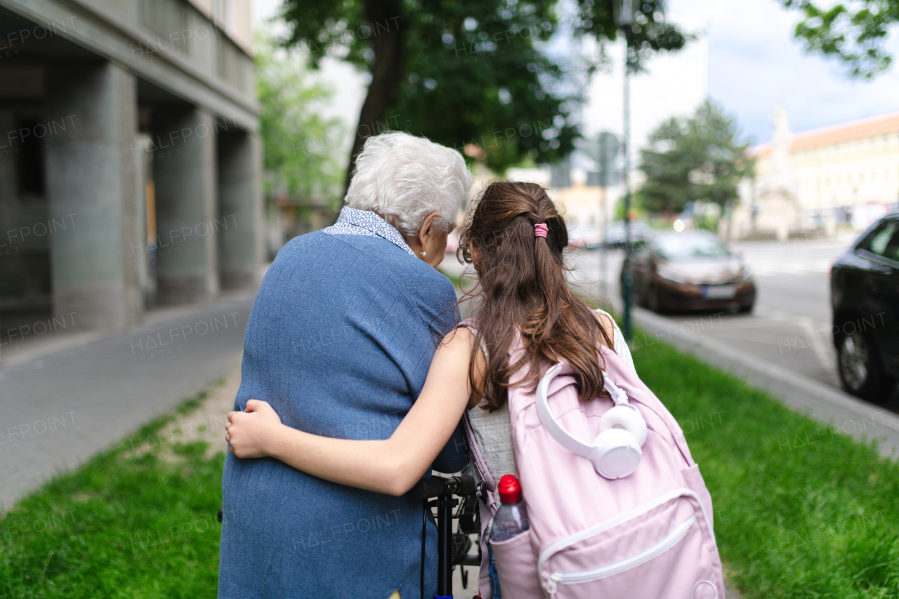 Grandma picking up girl after first day of school. Granddaughter spending time with her senior grandmother outdoors in the city, walking.