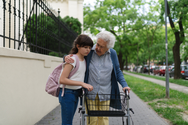 Grandma picking up girl after first day of school. Granddaughter spending time with her senior grandmother outdoors in the city.