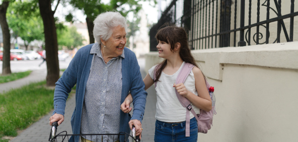 Grandma picking up girl after first day of school. Granddaughter spending time with her senior grandmother outdoors in the city.