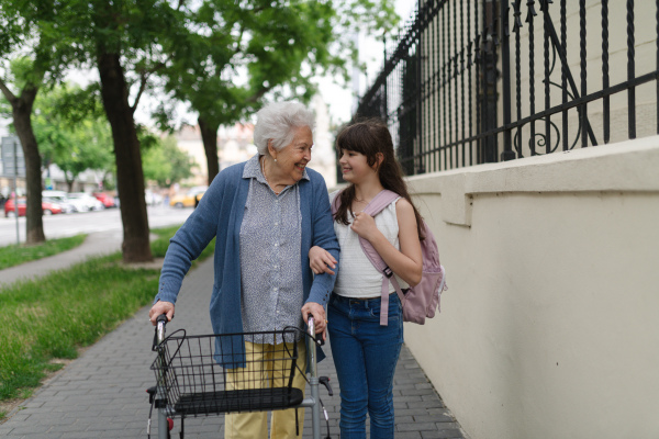 Grandma picking up girl after first day of school. Granddaughter spending time with her senior grandmother outdoors in the city.