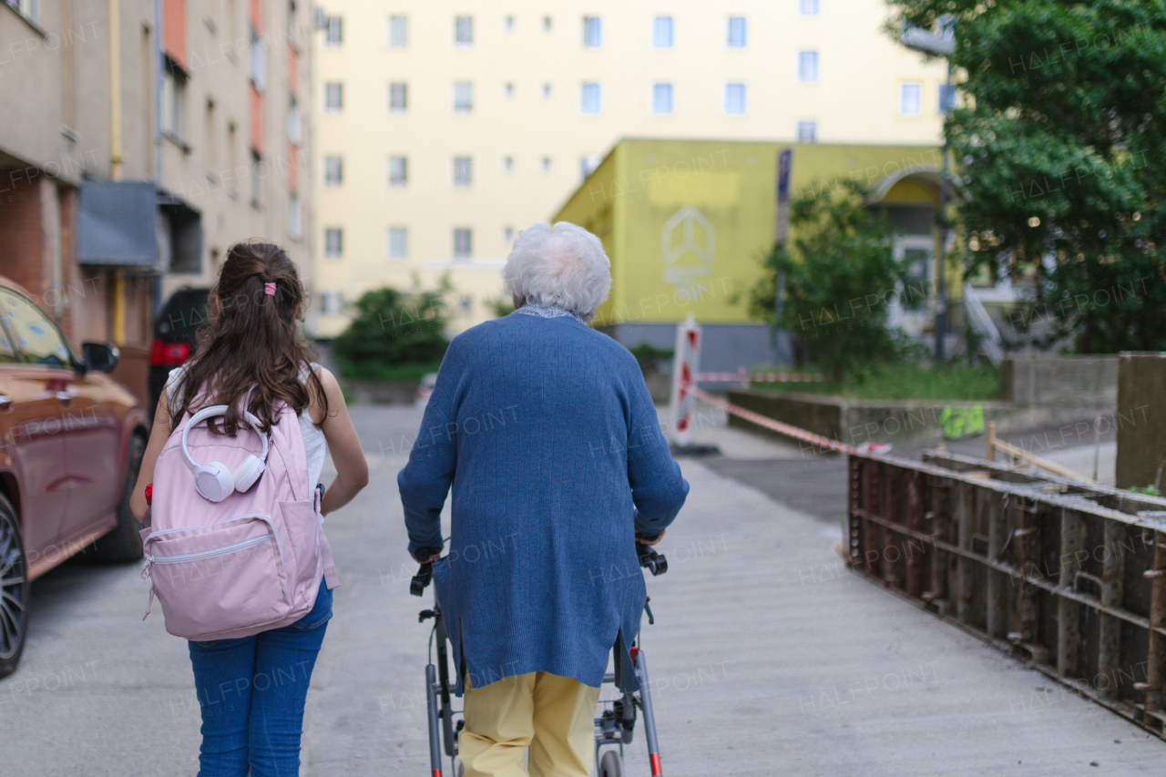 Grandma picking up girl after first day of school. Granddaughter spending time with her senior grandmother outdoors in the city.