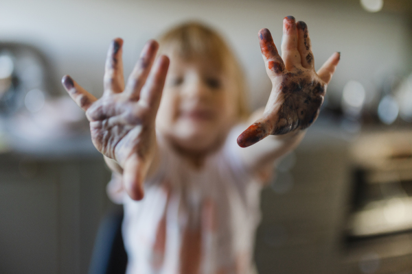 Cute little girl showing her messy hands stained with paint. Artistic kid getting messy and having fun.