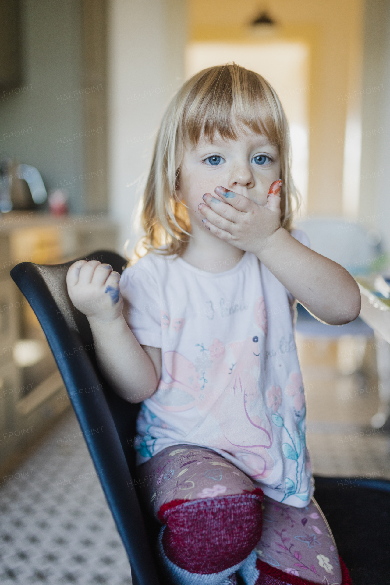 Portrait of little girl with messy hands stained with paint. Tired kid yawning after arts and crafts activities.