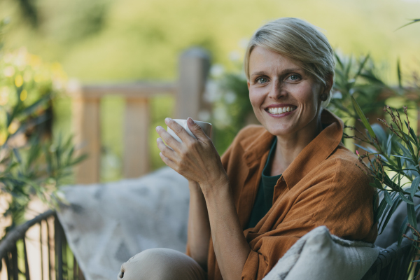 Beautiful woman relaxing in the garden, drinking cup of coffee. Mother having a moment to herself while her child is sleeping.