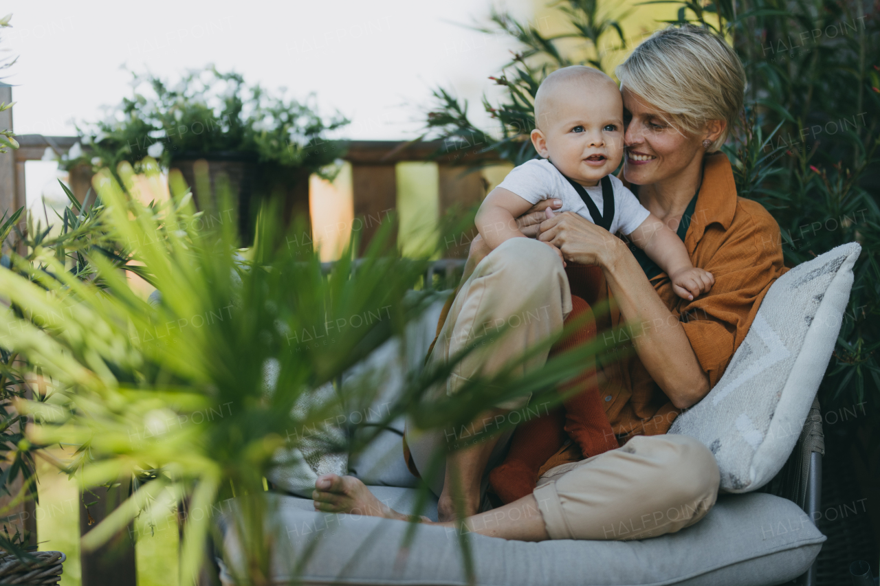 Beatiful mother sitting with her little son outdoors, in the garden patio. Warm autumn day of mother with toddler. Hygge motherhood.