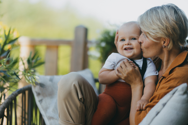 Beatiful mother sitting with her little son outdoors, in the garden patio. Warm spring day of mother with toddler. Hygge motherhood.