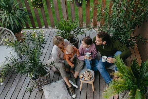 Top view of family having a snack outdoors in the garden patio, drinking warm tea and eating sweet roll bread. Hygge family autumn time.