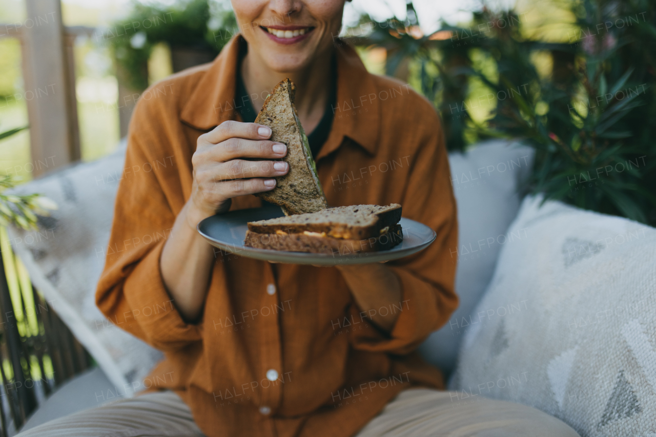 Beautiful woman relaxing in the garden, eating sandwich. Mother having a moment to herself while her child is sleeping, eating lunch or dinner in peace.