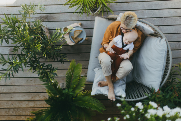 Top view of beatiful mother sitting with her little son outdoors, in the garden patio. Warm autumn day of mother with toddler. Hygge motherhood.