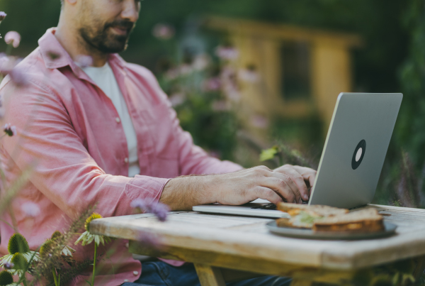 Man working outdoors in the garden, eating lunch or snack, sandwich. Businessman working remotely from homeoffice, thinking about new business or creative idea.