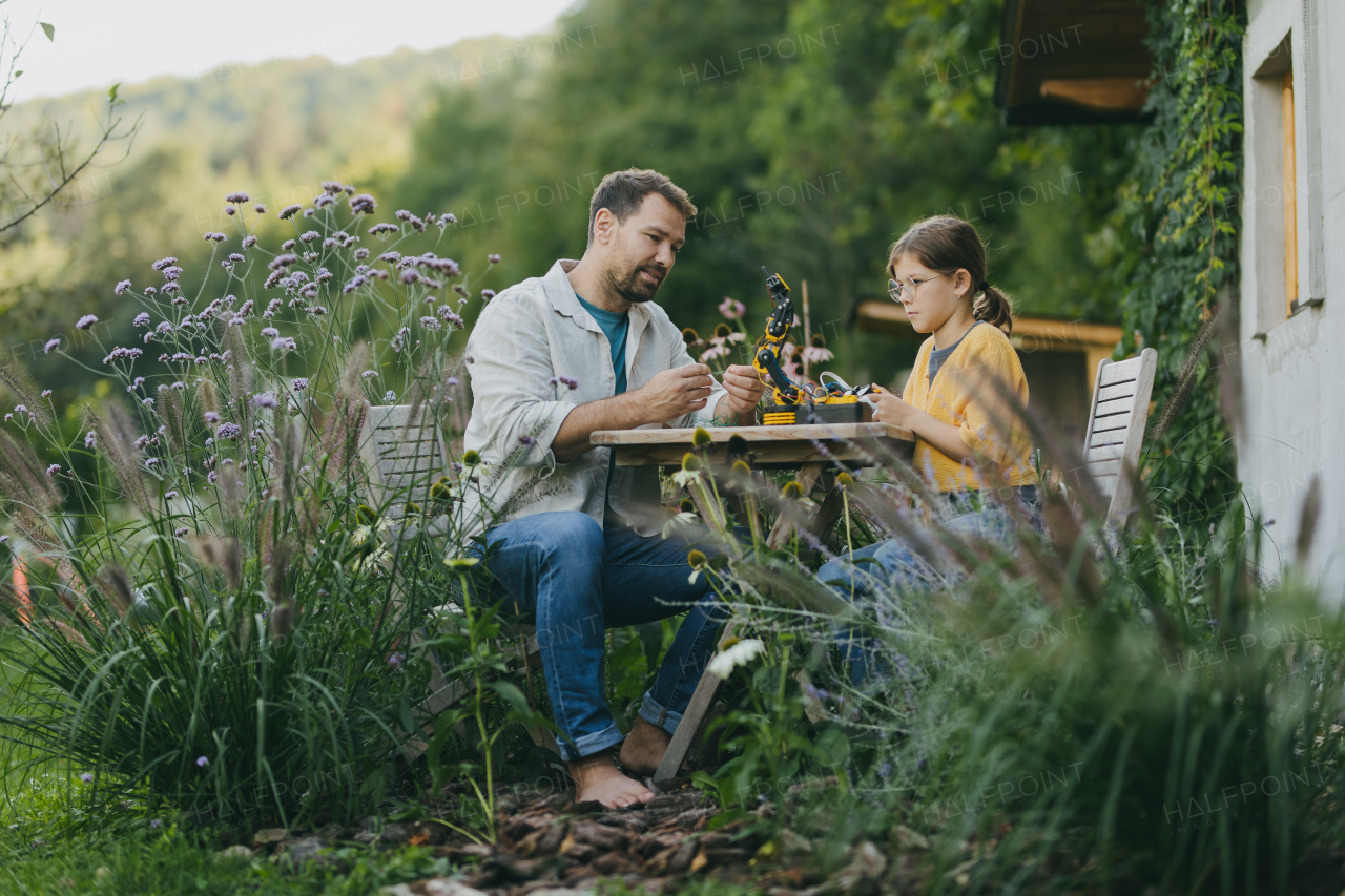 Young girl assembling a simple robot, father helping her. Father supporting daughter in pursuing robotics, science, IT technologies and programming.