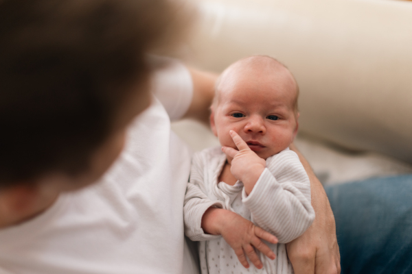 A father holding his newborn son at home.