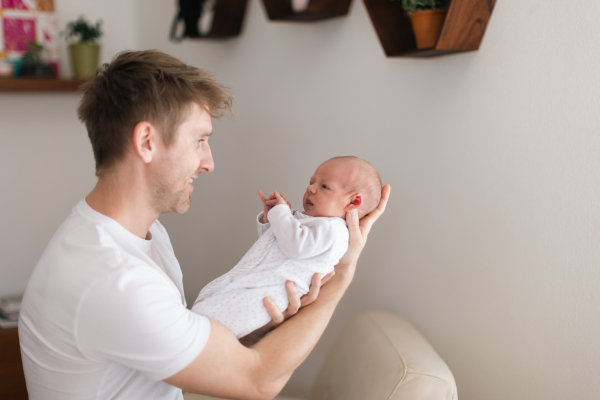 A father holding his newborn son at home.